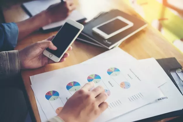 a person holding a phone and looking at a graph